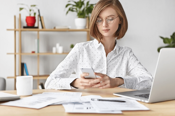 a woman in an office sending a text message