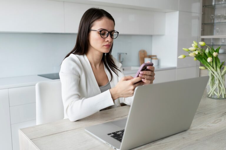 Woman using a laptop and a phone at home
