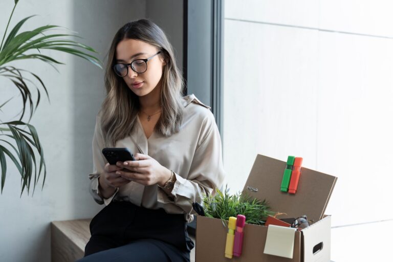 Woman using her phone and sitting on a desk
