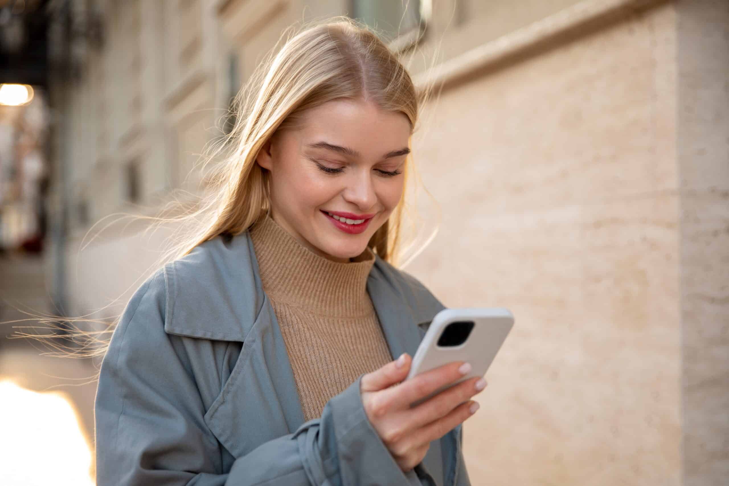 A woman smiles while using her phone