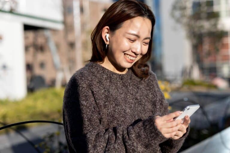 A woman smiling while using her phone