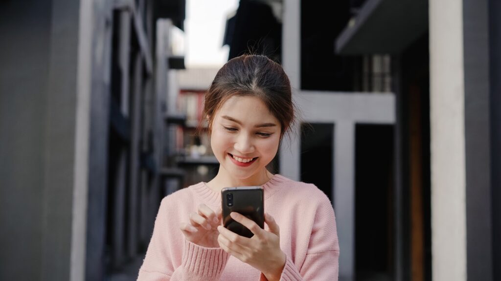 A woman smiling while using a smartphone